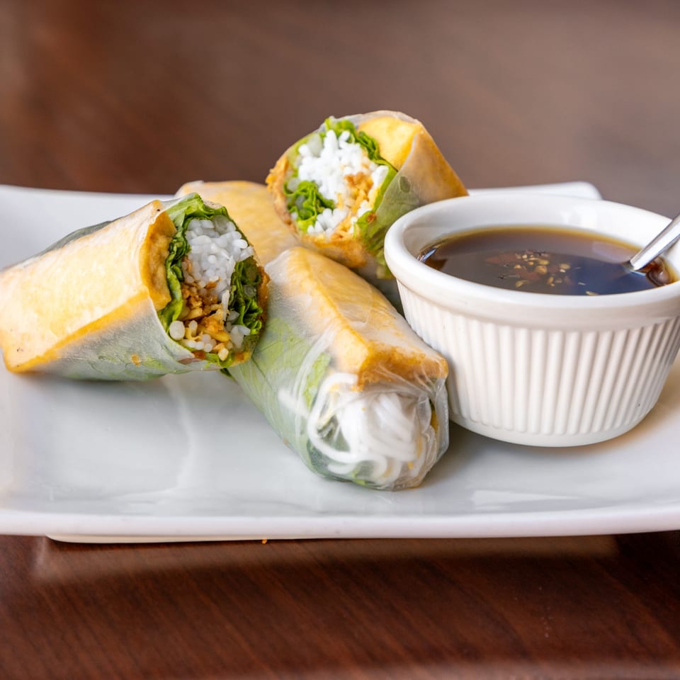 Fresh Vietnamese spring rolls filled with rice noodles, lettuce, and tofu, served with a dark dipping sauce.